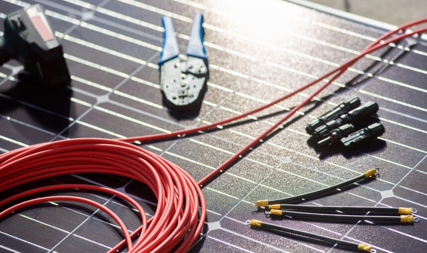 Close-up view of different details and instruments for mounting and connecting solar photovoltaic system. Objects laying on blue solar panel. Alternative energy resources renewable ecologycal concept.