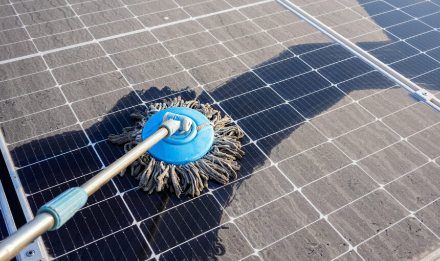 Man clean up the solar panels that are dirty with dust and birds' droppings to improve the efficiency of solar energy storage.